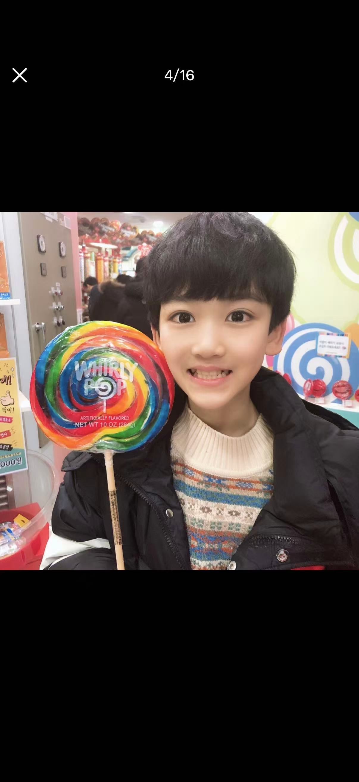 小时候的邓佳鑫笑着拿着彩色棒棒糖
